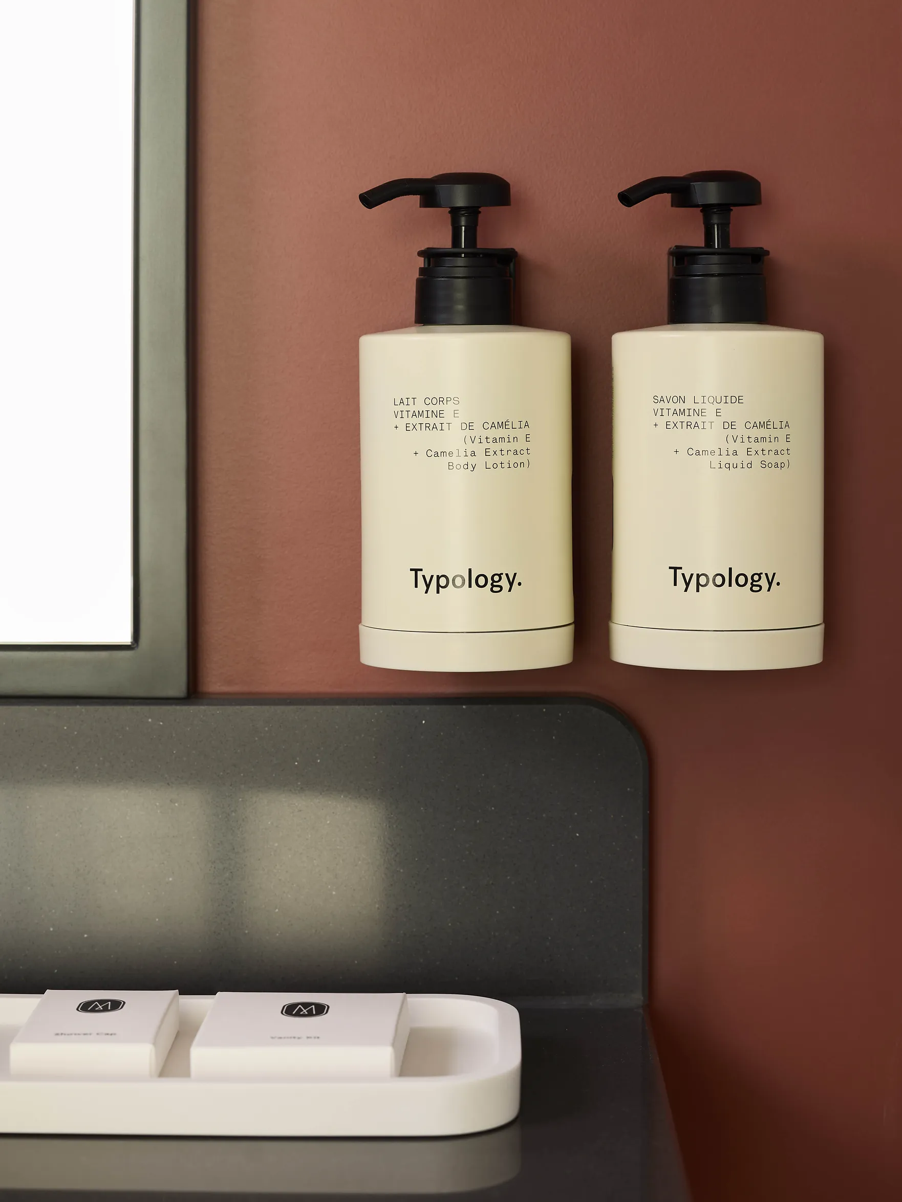 Duo de flacons de soins hotel sur tablette de salle de bain, fond terracotta