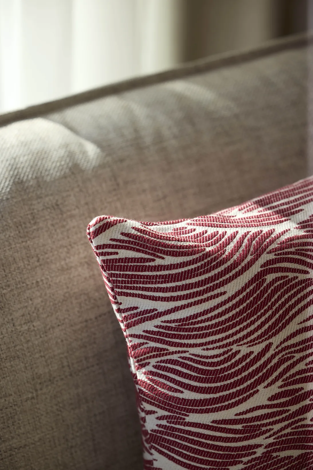 Coussin rayé bordeaux et blanc sur canapé en tissu gris