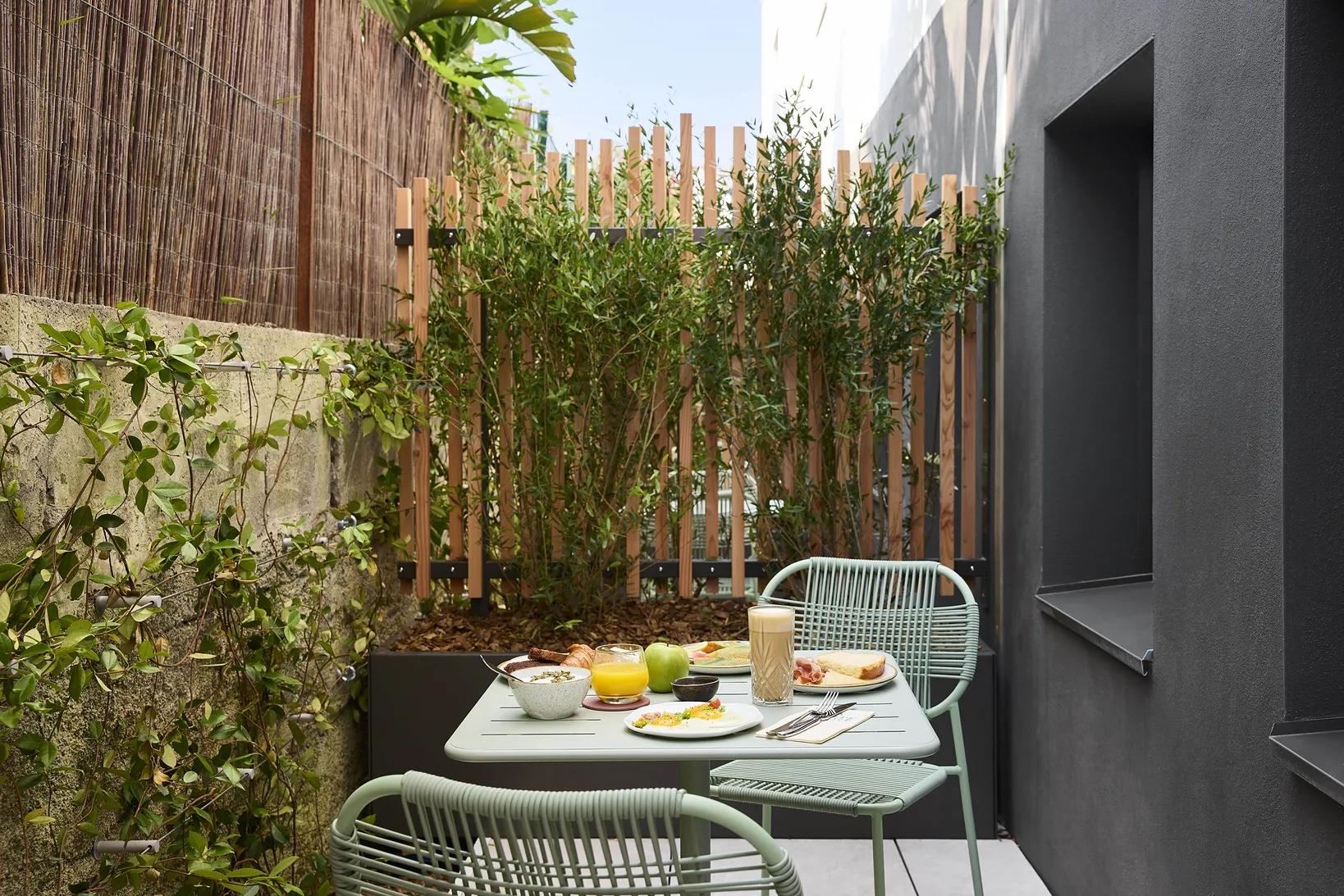 Terraza privada del hotel con mesa y sillas de jardín, rodeada de bambúes y vegetación