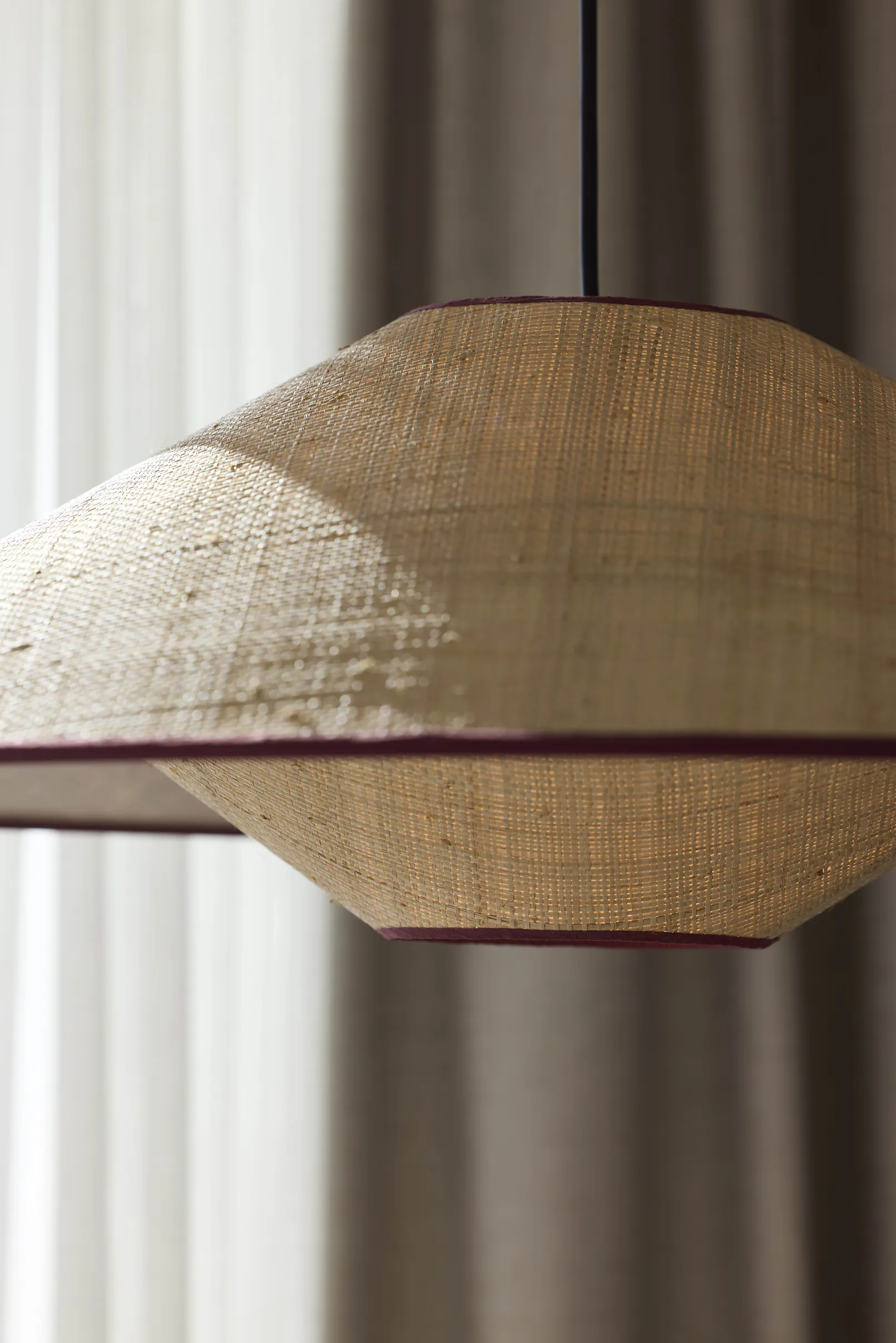 Luminaire en raphia naturel avec liseré bordeaux dans une chambre de l'hôtel Le Talaia Mgallery Biarritz