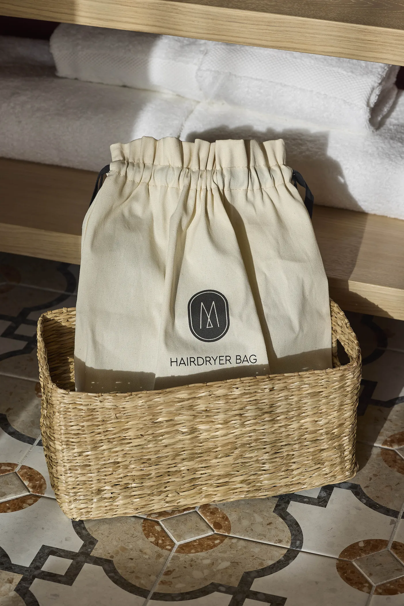 Pochette en lin et panier tressé en osier dans une chambre de l'hôtel Le Talaia Mgallery Biarritz