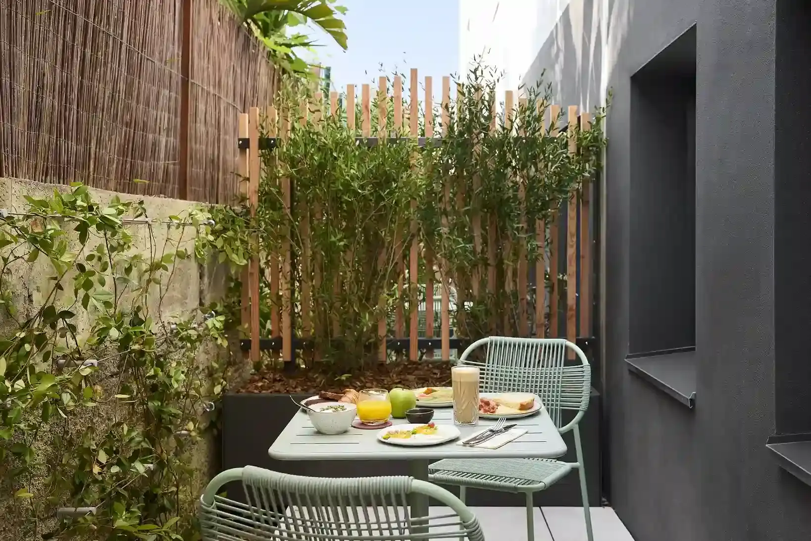 Terrasse privée d'hôtel avec table et chaises de jardin, entourée de bambous et végétation