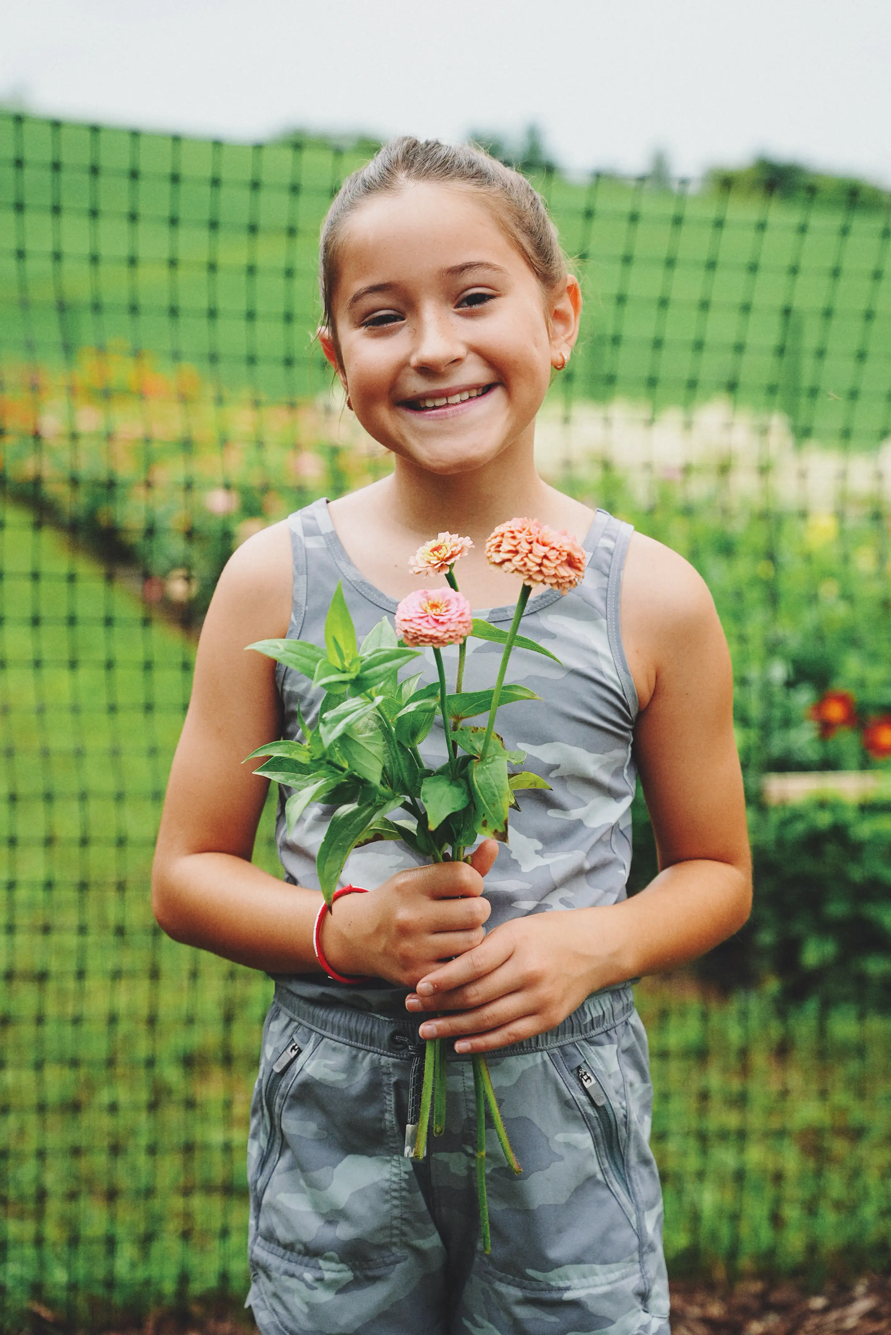 A child holding a small bunch of zinnias in the flower field.