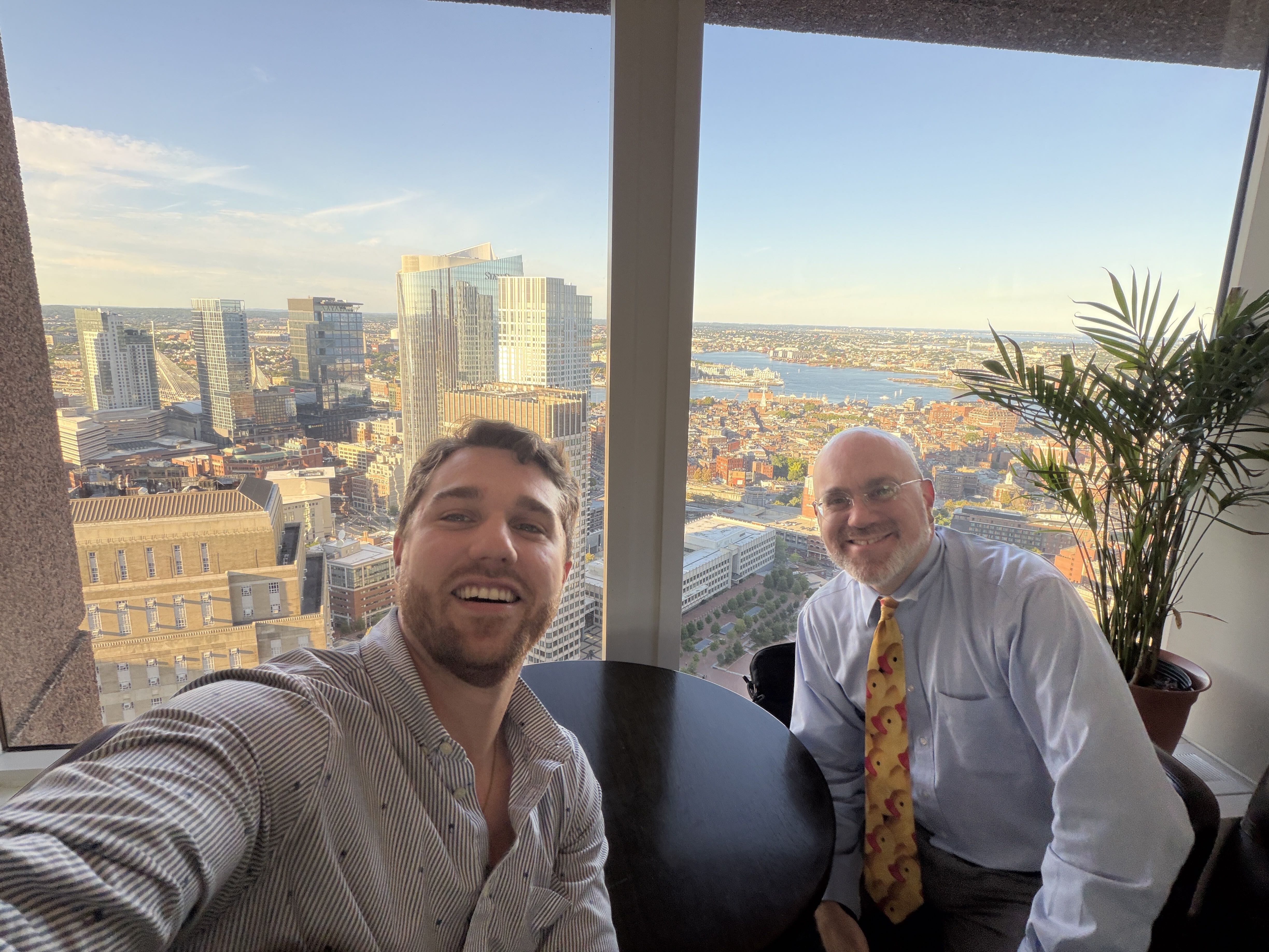 Joe Khoury and Paul Silva at the UMass Club with the Boston skyline behind them