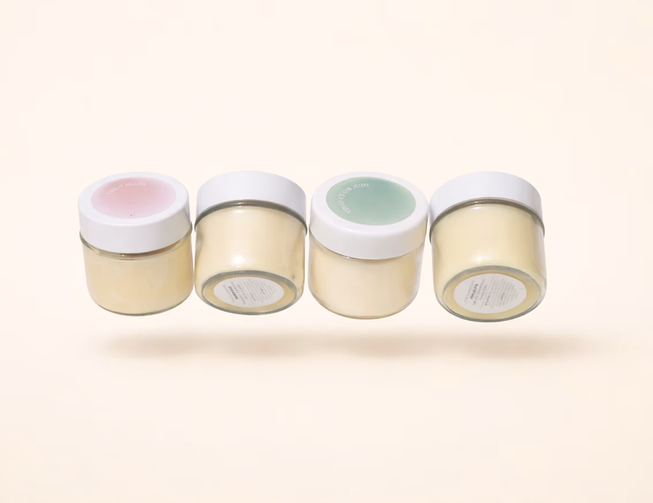 Four small glass candles with white lids in a row against a beige background. Credit: May-lee Abel, Chatgpt