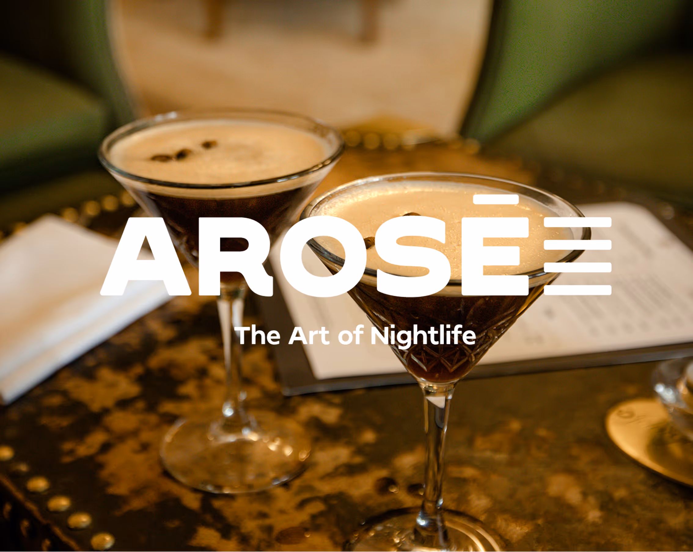 Two espresso martinis on a table with menu and napkin, text reads AROSÉ The Art of Nightlife. Credit: Unsplash