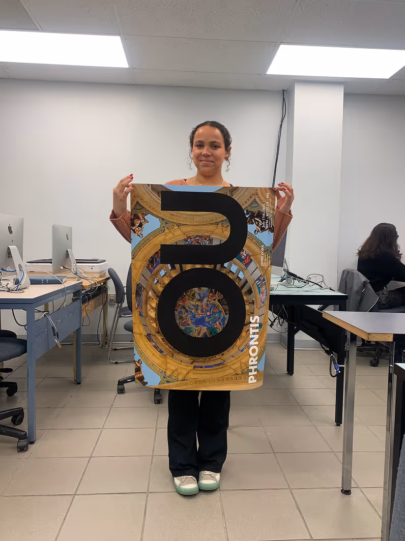 May-lee standing in office holding a large decorative poster with the word OU PHRONTIS.