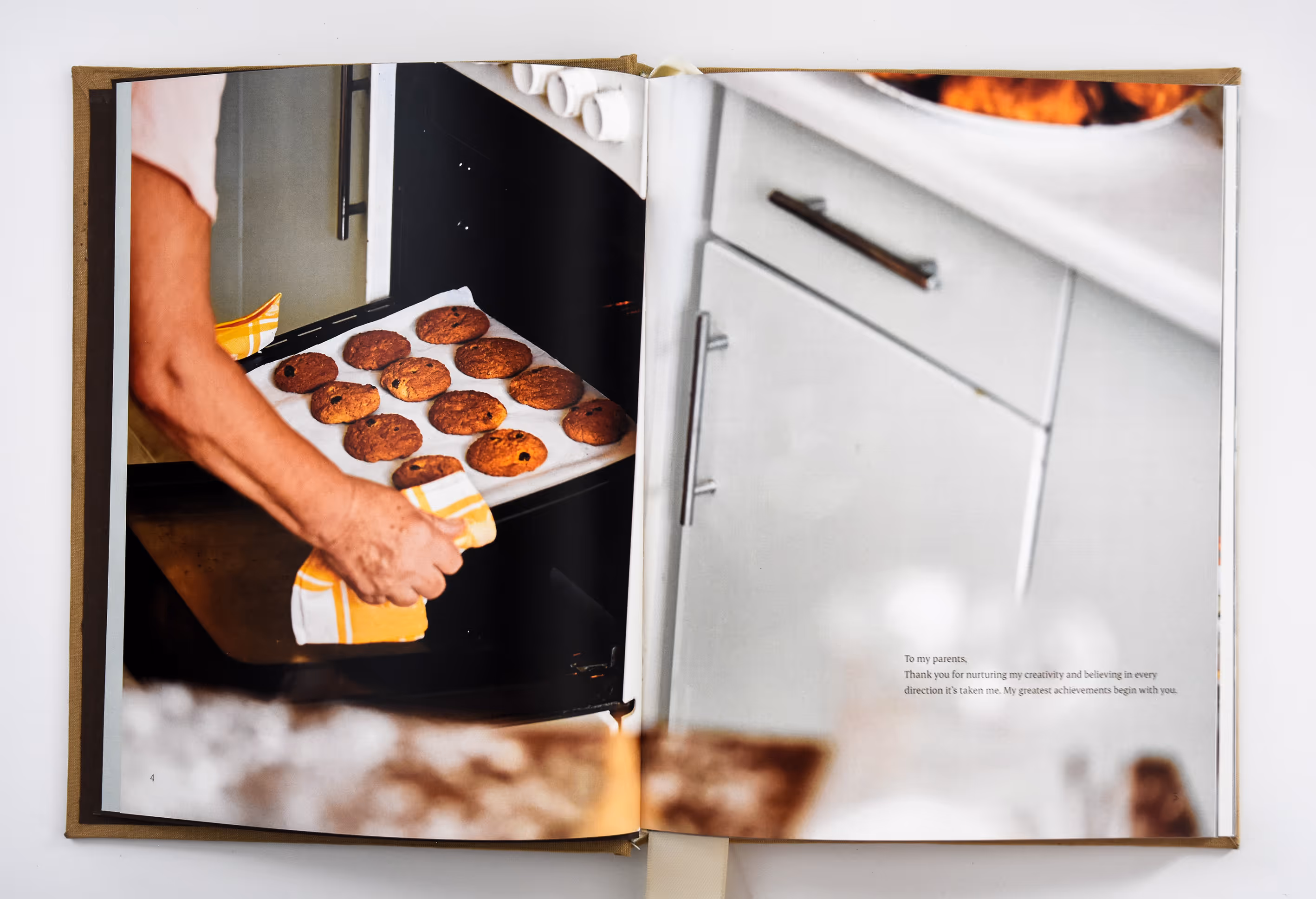 Person using a yellow-striped oven mitt to take a tray of chocolate chip cookies out of the oven. Credit: May-Lee Abel
