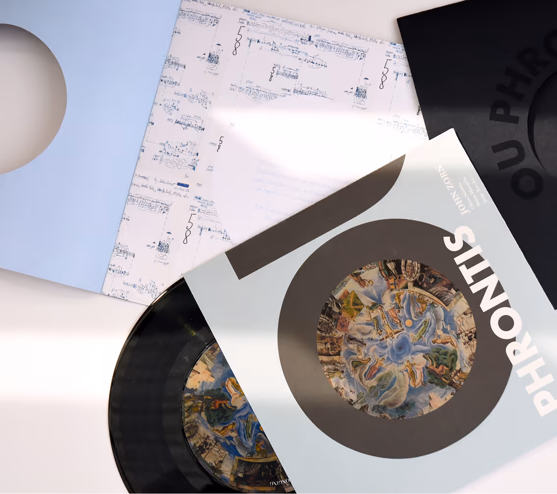 Vinyl record partially pulled from cover titled 'PHRONIS' with artwork and sheet music sleeves nearby. Credit: May-Lee Abel