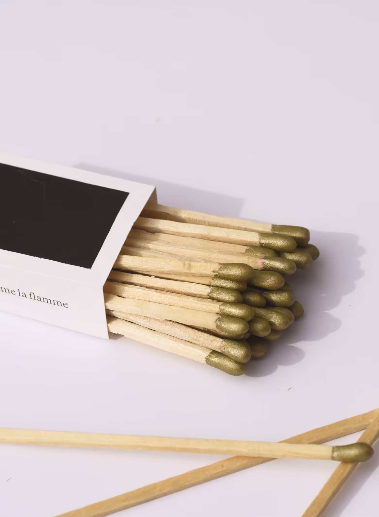 White matchbox with gold-tipped wooden matches spilling out on a light surface. Credit: May-Lee Abel