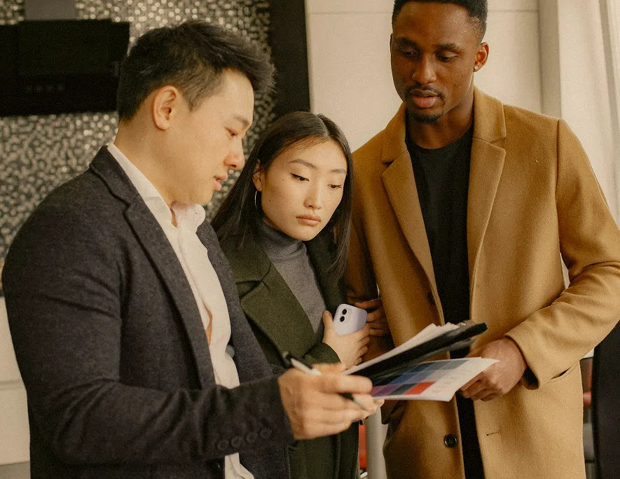 Three diverse professionals reviewing color samples and documents together indoors.