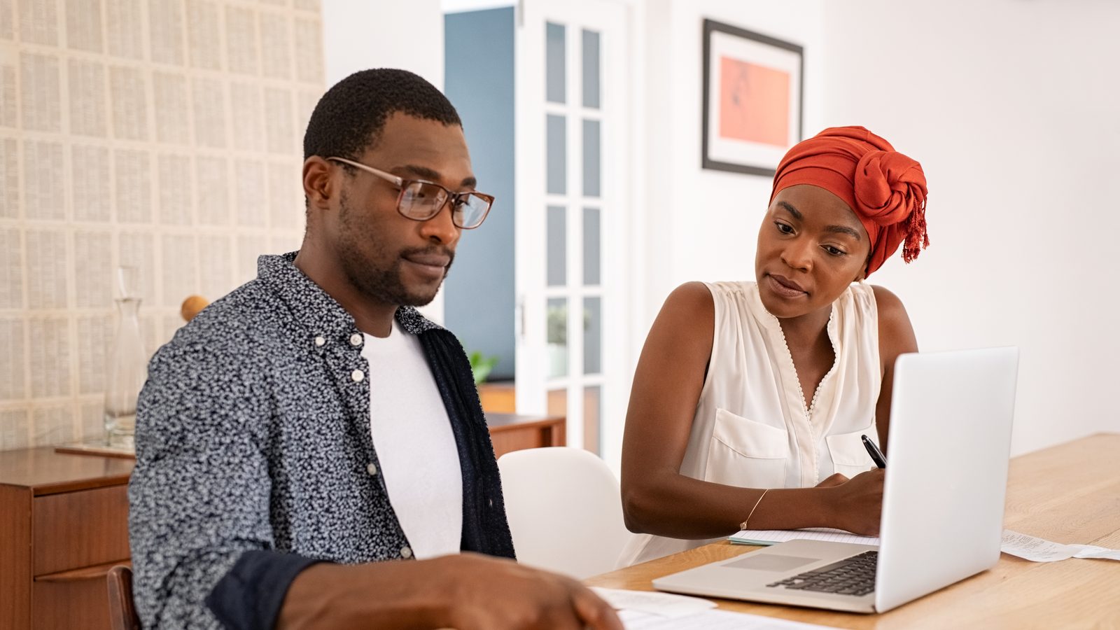 Couple reviewing paperwork with a laptop at their dining table