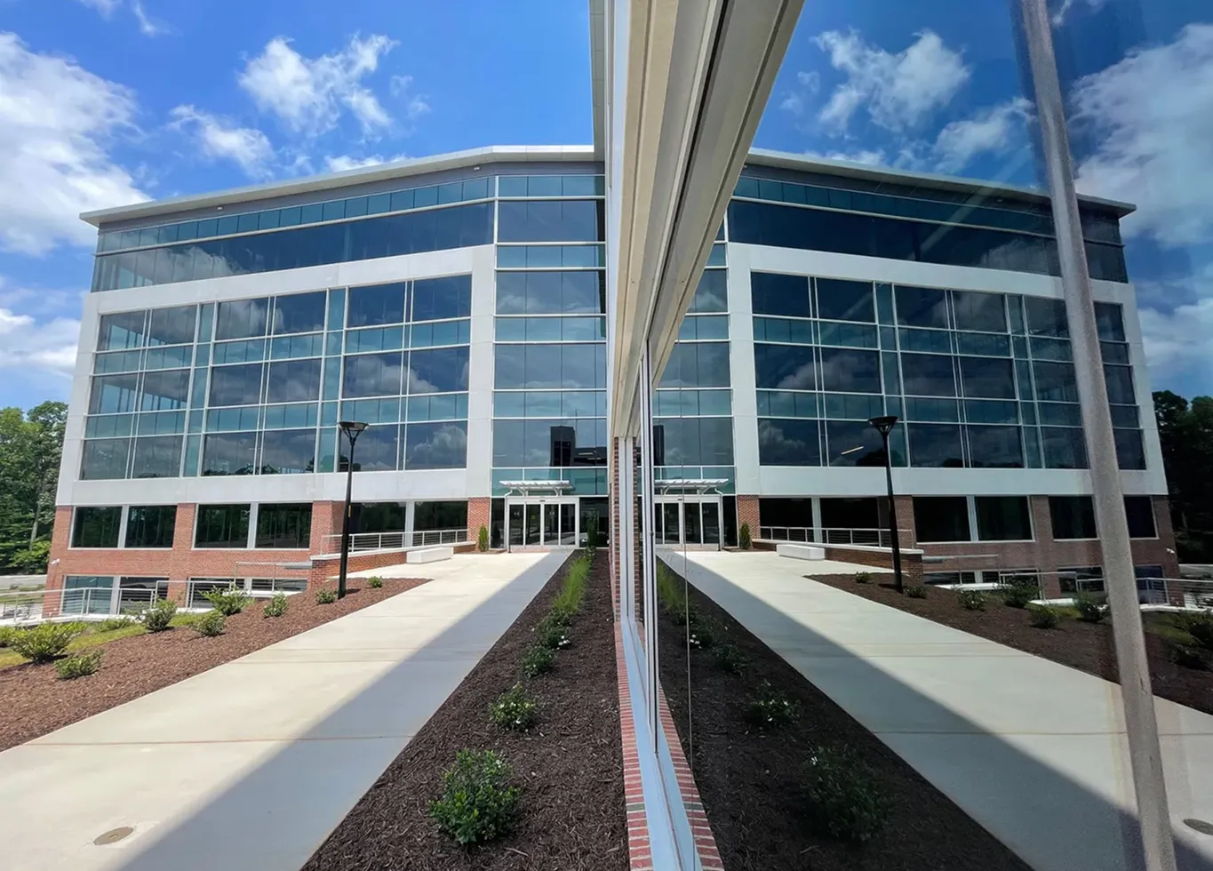Exterior view of the Pallisades office building in Raleigh, NC featuring a multi-story reflective glass curtain wall system installed by BrightLeaf Glass and Metal