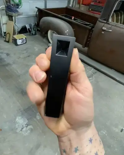 Black Abyss Tempest pipe held in hand inside garage with vintage truck in background