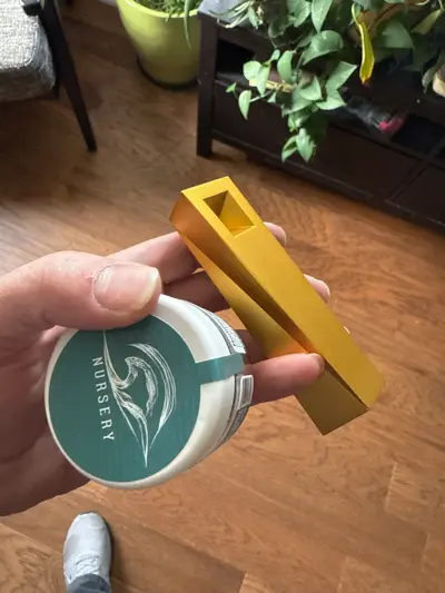 Gold Radiance Tempest pipe held in hand next to small container indoors