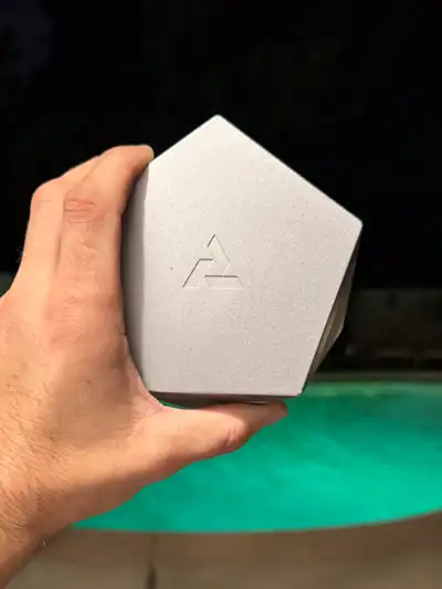 Silver Mercury Vesta magnetic vessel held in hand with Artifact logo against poolside background