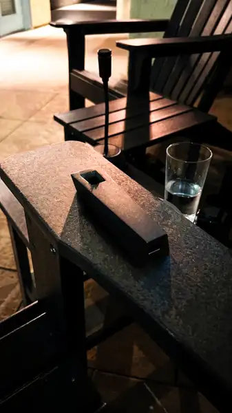 Black Abyss Tempest pipe resting on outdoor table beside glass and incense holder at night