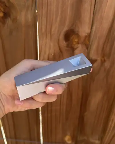 Silver Mercury Tempest pipe held in hand against wooden fence in daylight