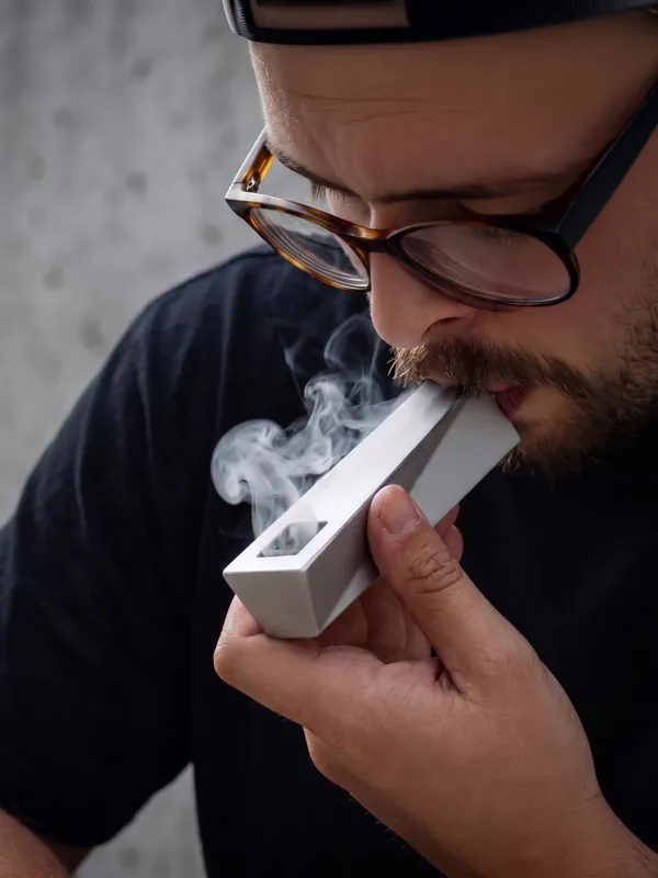 Silver Mercury Tempest pipe used by person with visible smoke and soft lighting