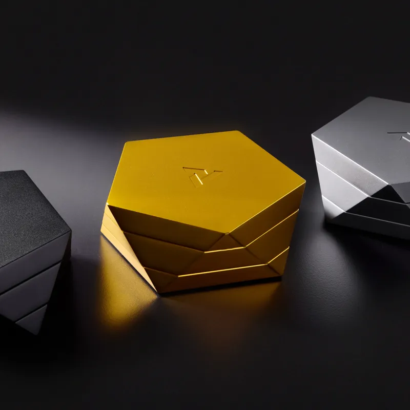 Vesta magnetic ashtray in gold centered between black and silver Vesta ashtrays on a dark reflective surface