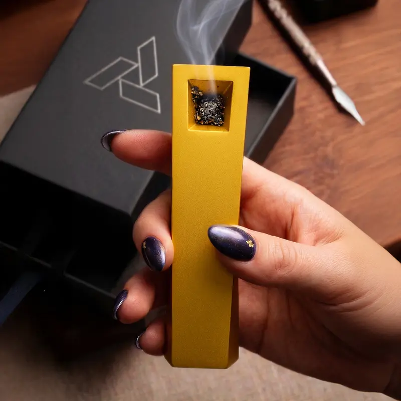 Gold Tempest pipe in hand with smoke rising beside open Artifact packaging