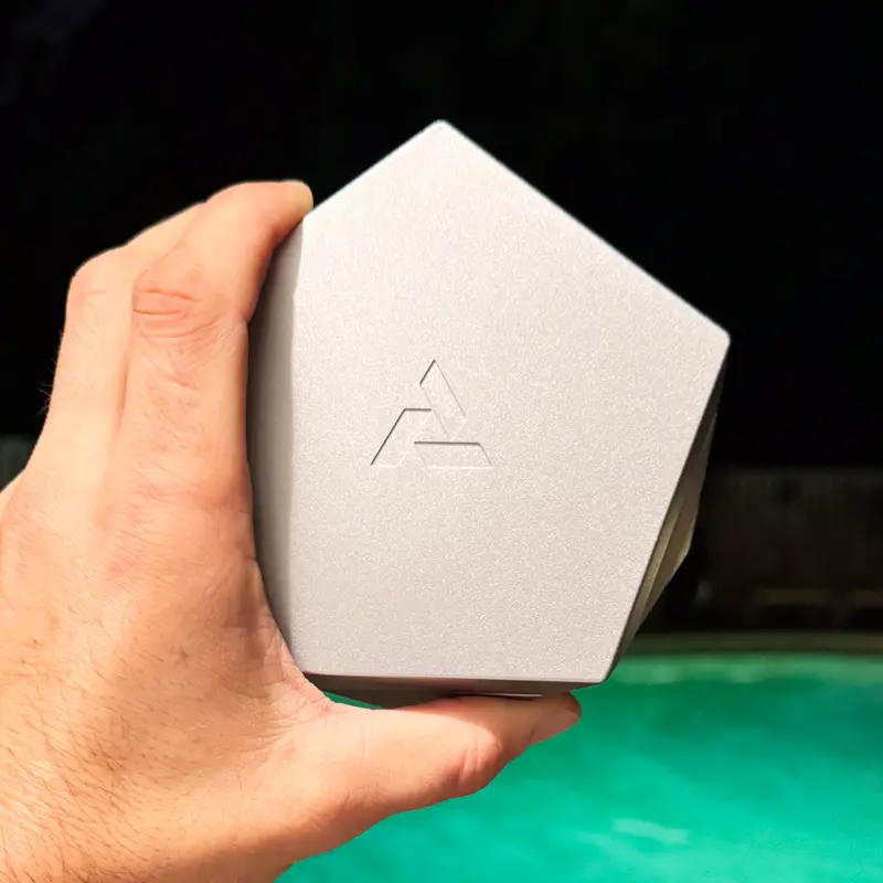 Silver Vesta anodized aluminum container held beside illuminated turquoise pool at night
