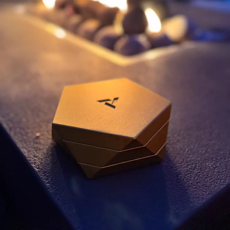 Gold Vesta magnetic ashtray beside outdoor firepit with warm evening lighting