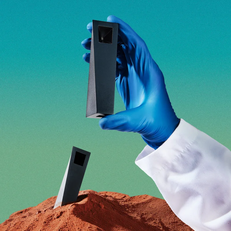 Black Tempest pipe lifted from red sand by gloved hand in surreal desert composition