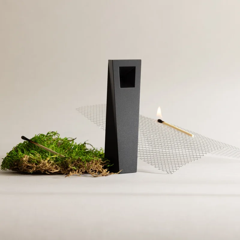 Black Tempest magnetic pipe displayed with moss and flame in minimalist studio composition