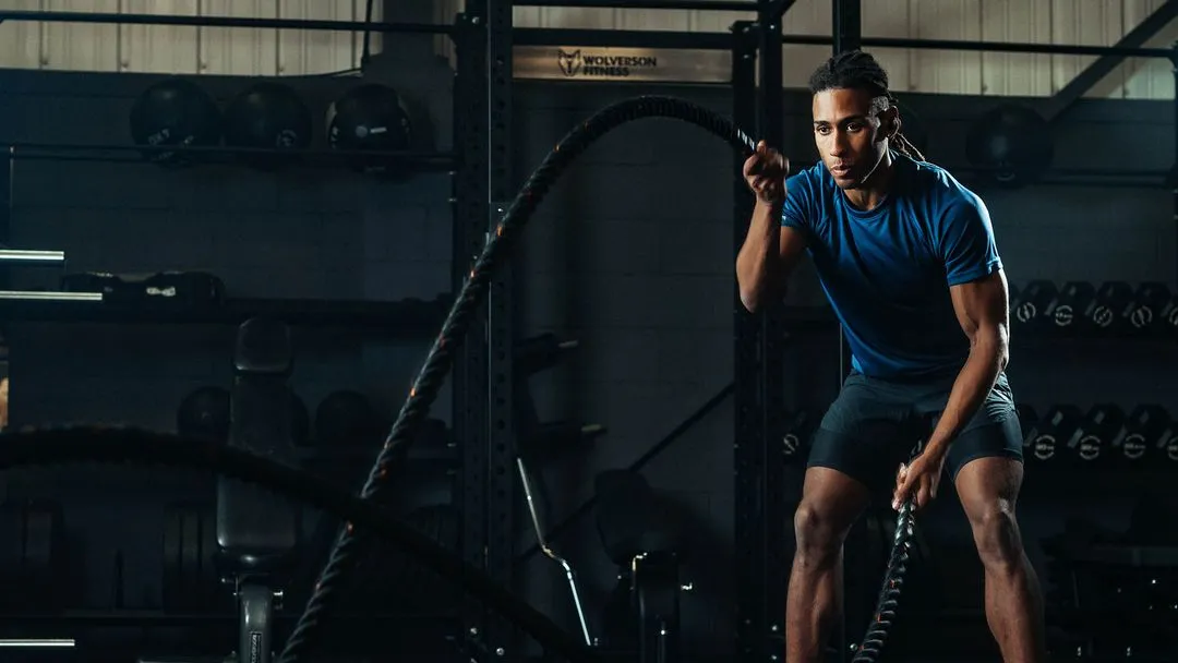 A man in a gym using battle ropes