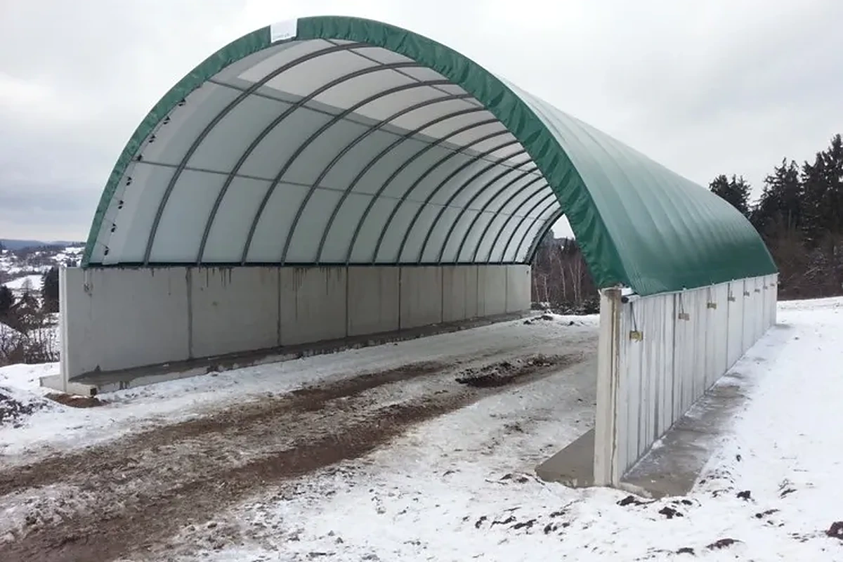 Plachtová hala se zelenou střechou na betonových stěnách v zimě