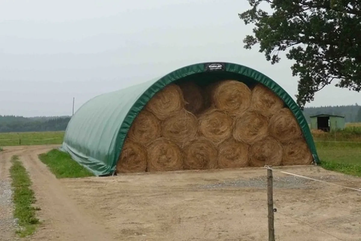 Plachtová hala zaplněná kulatými balíky sena