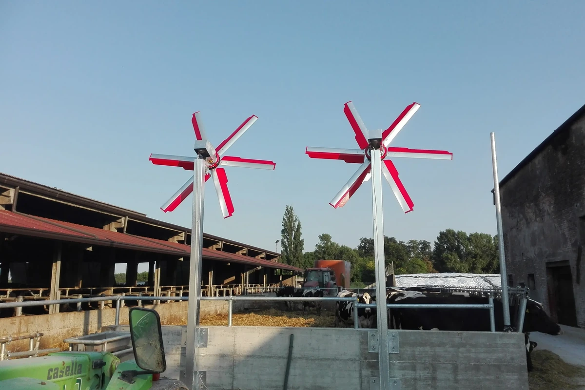 Dva vertikální ventilátory na sloupech nad venkovním výběhem proti modré obloze