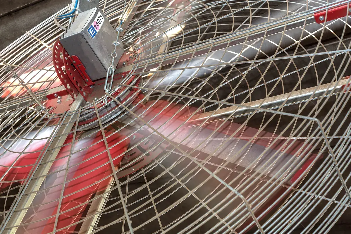 Vertikální ventilátor s ochrannou mříží zavěšený nad boxy