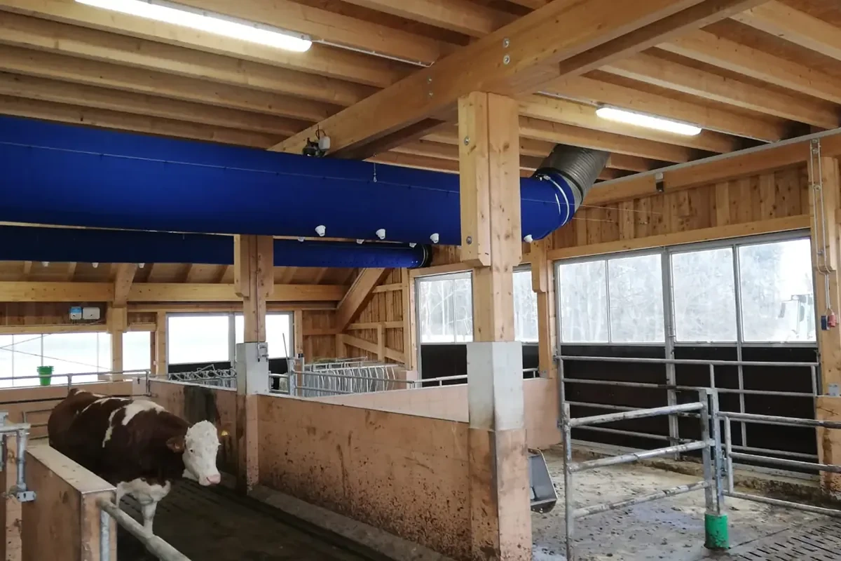 Modrý ventilační tubus zavěšený pod dřevěnou konstrukcí odchovny