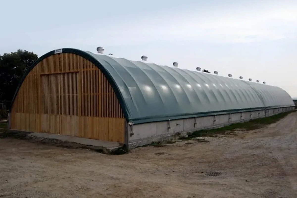 Řada ventilačních turbín na hřebeni obloukové haly s dřevěným štítem