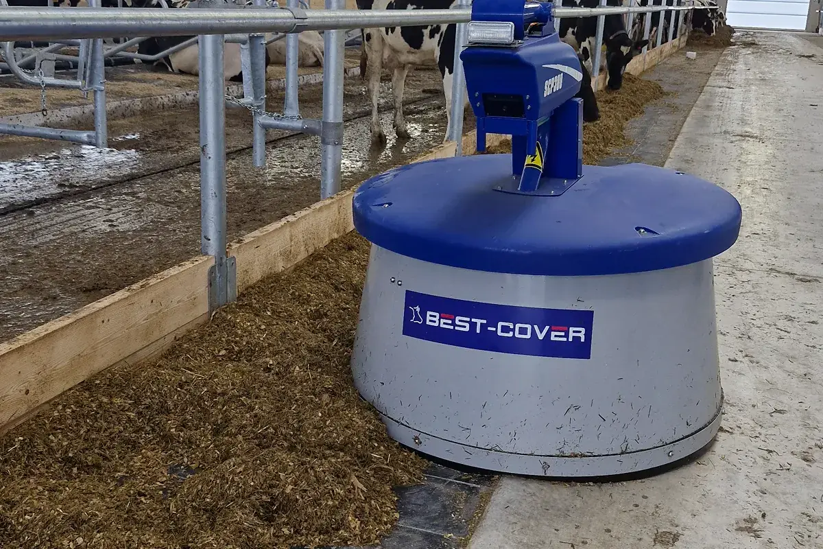 Robot Nimbo s logem Best-Cover na krmné chodbě mezi dojnicemi