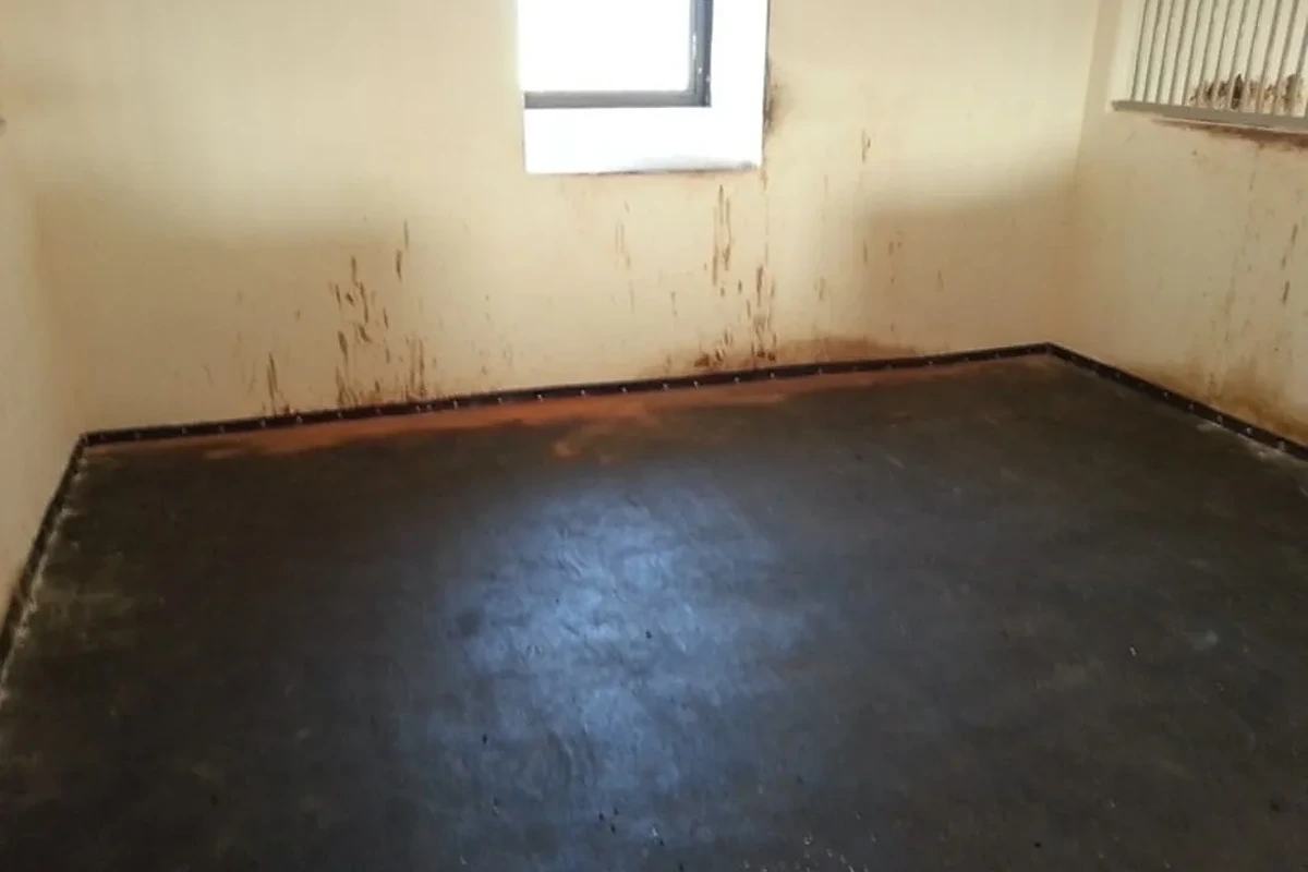 Matrace položená v rohu boxu s bílými stěnami