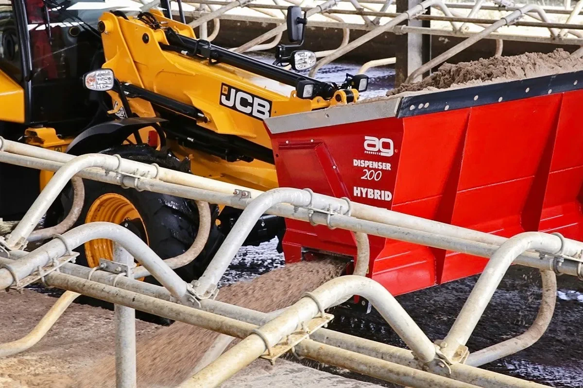 Nesený zásobník AG Dispenser na nakladači JCB nad lehacími boxy