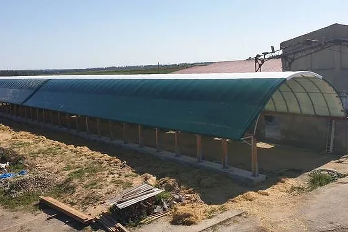 Dlouhá plachtová hala SAS se zelenou membránou na zpevněné ploše