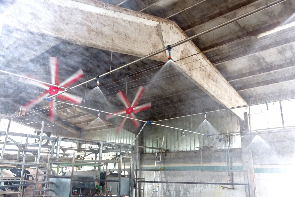 Mlžicí trysky a ventilátory v provozu pod stropem stáje