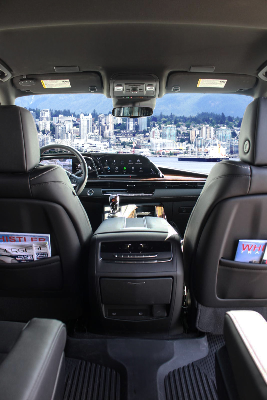 Interior view of Escalade, a modern Luxury SUV featuring black leather seats, central touchscreen dashboard, and a cityscape visible through the windshield.