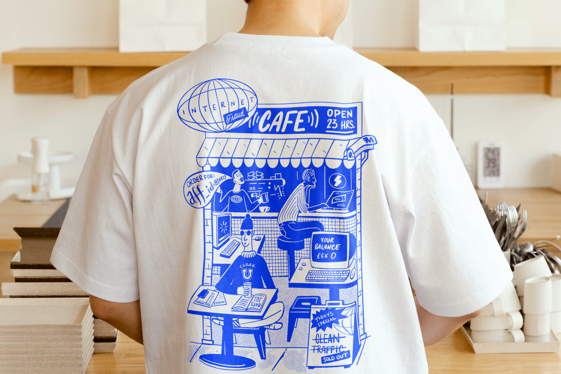 White t-shirt with blue cartoon of an internet cafe scene showing computers and people inside.