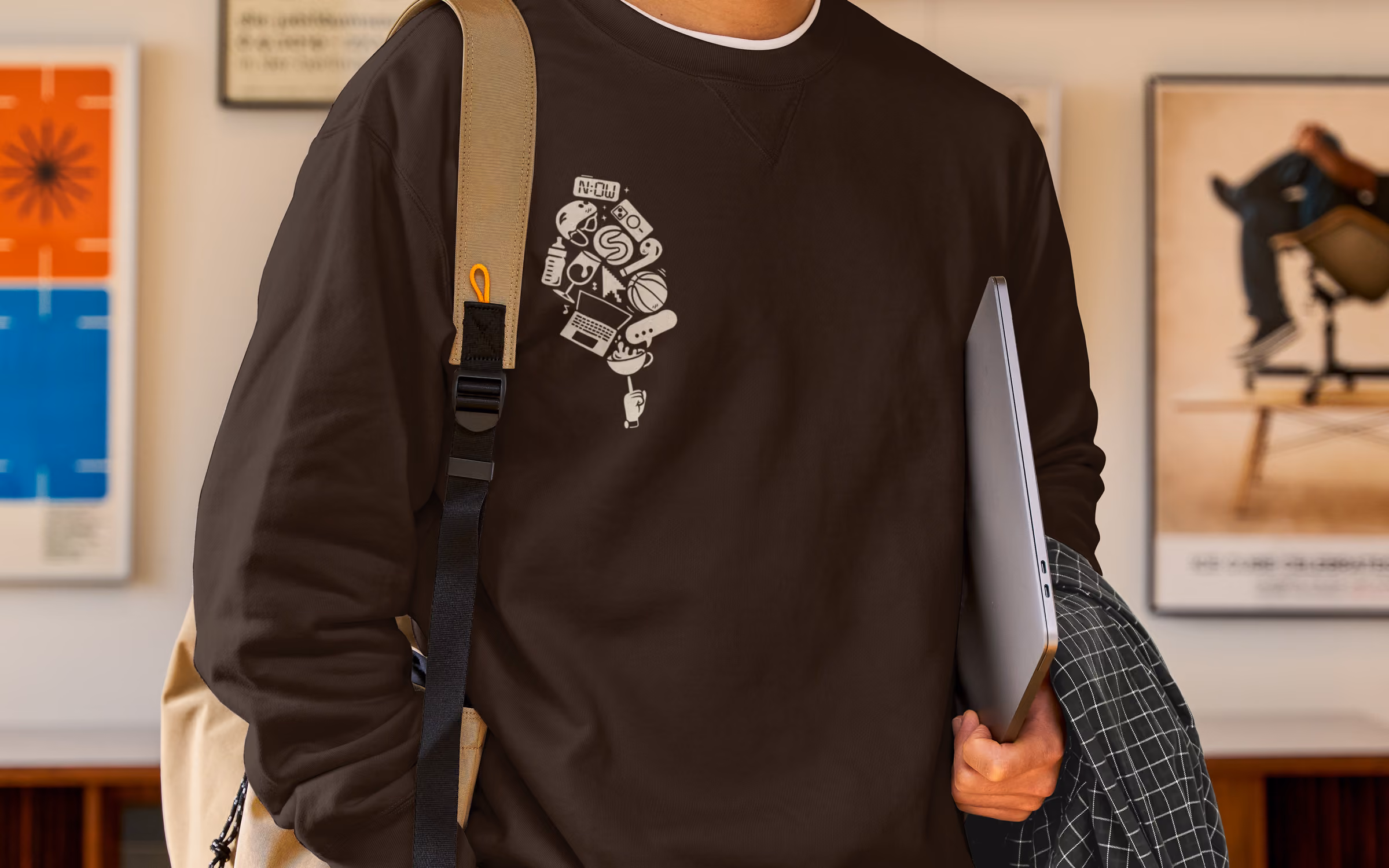 Person wearing dark brown sweatshirt with white graphic icons forming a light bulb shape on chest.