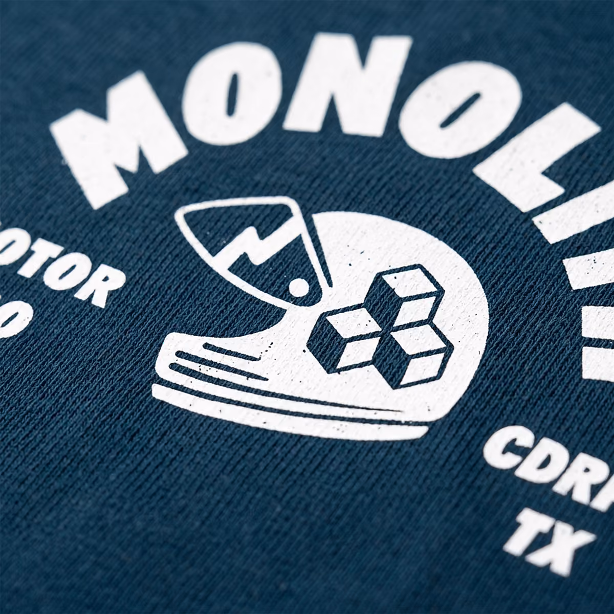 Close-up of a blue fabric with white print of a helmet, cubes, and text including MOTOR and TX.