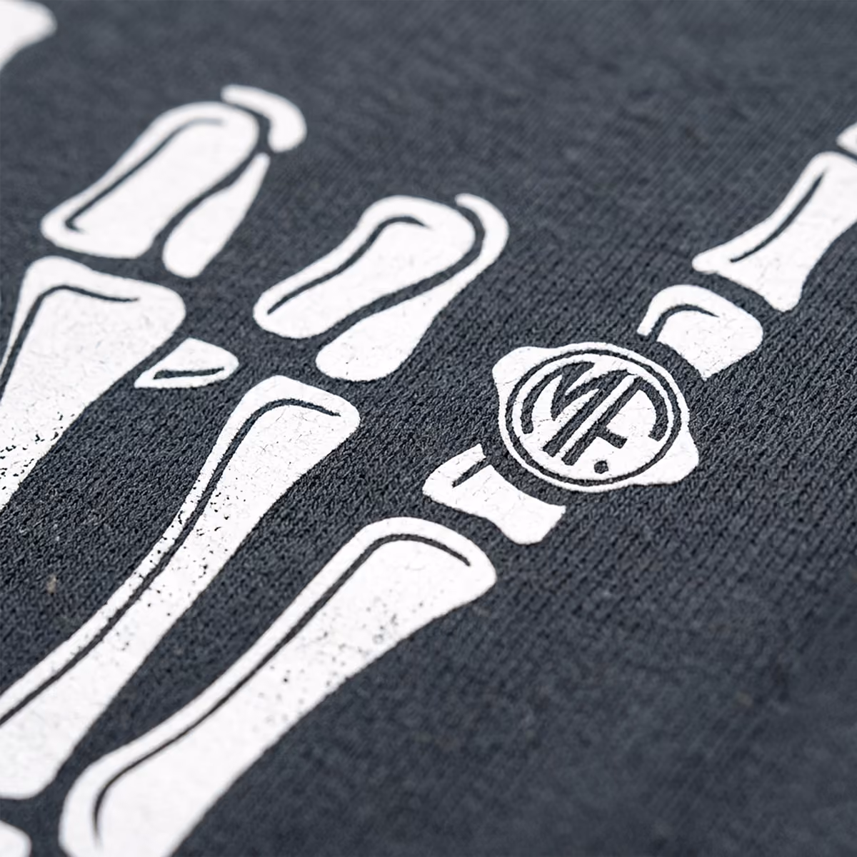 Close-up of a white skeleton hand print on a textured dark fabric surface.