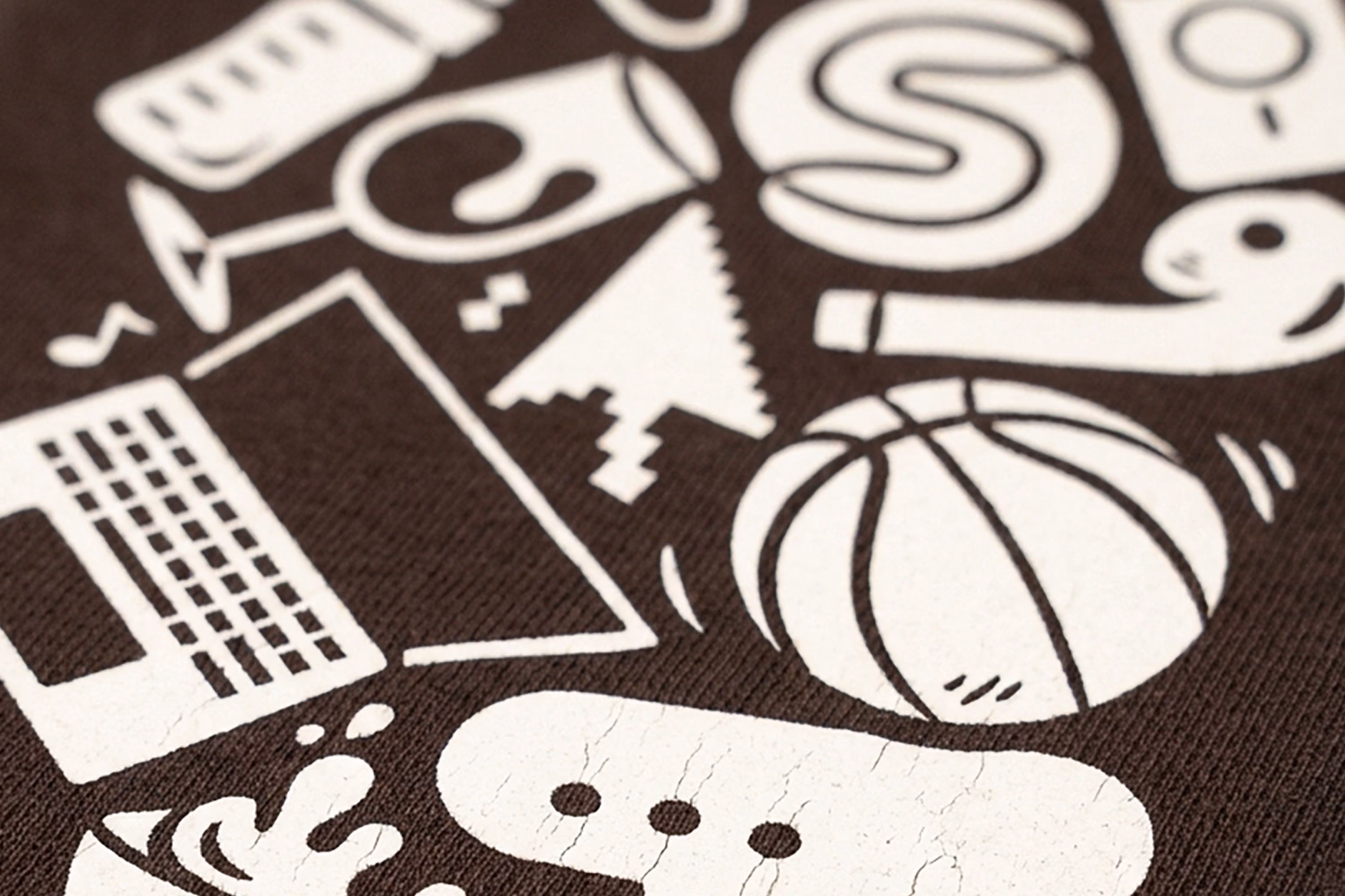Close-up of a textured surface with white graphic icons including a laptop, computer cursor, basketball, and stylized letters on a dark background.