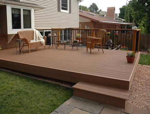 Composite wood deck with black metal railing, two wicker chairs and a small table overlooking a backyard in Wittenberg Wisconsin