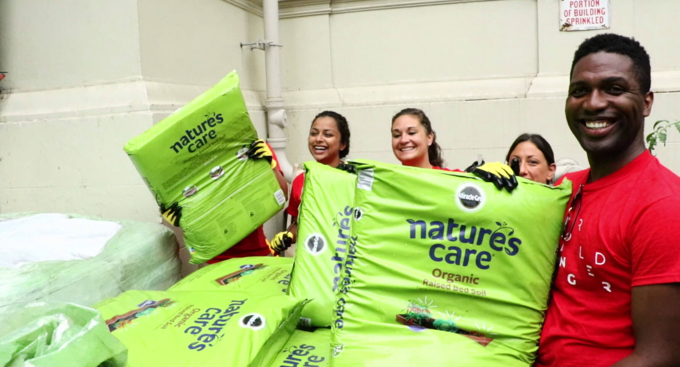 Volunteers carrying bags of Nature's Care organic soil