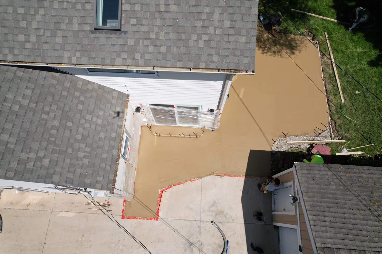Aerial view of freshly poured concrete patio base drying next to residential home, Grand Rapids MI